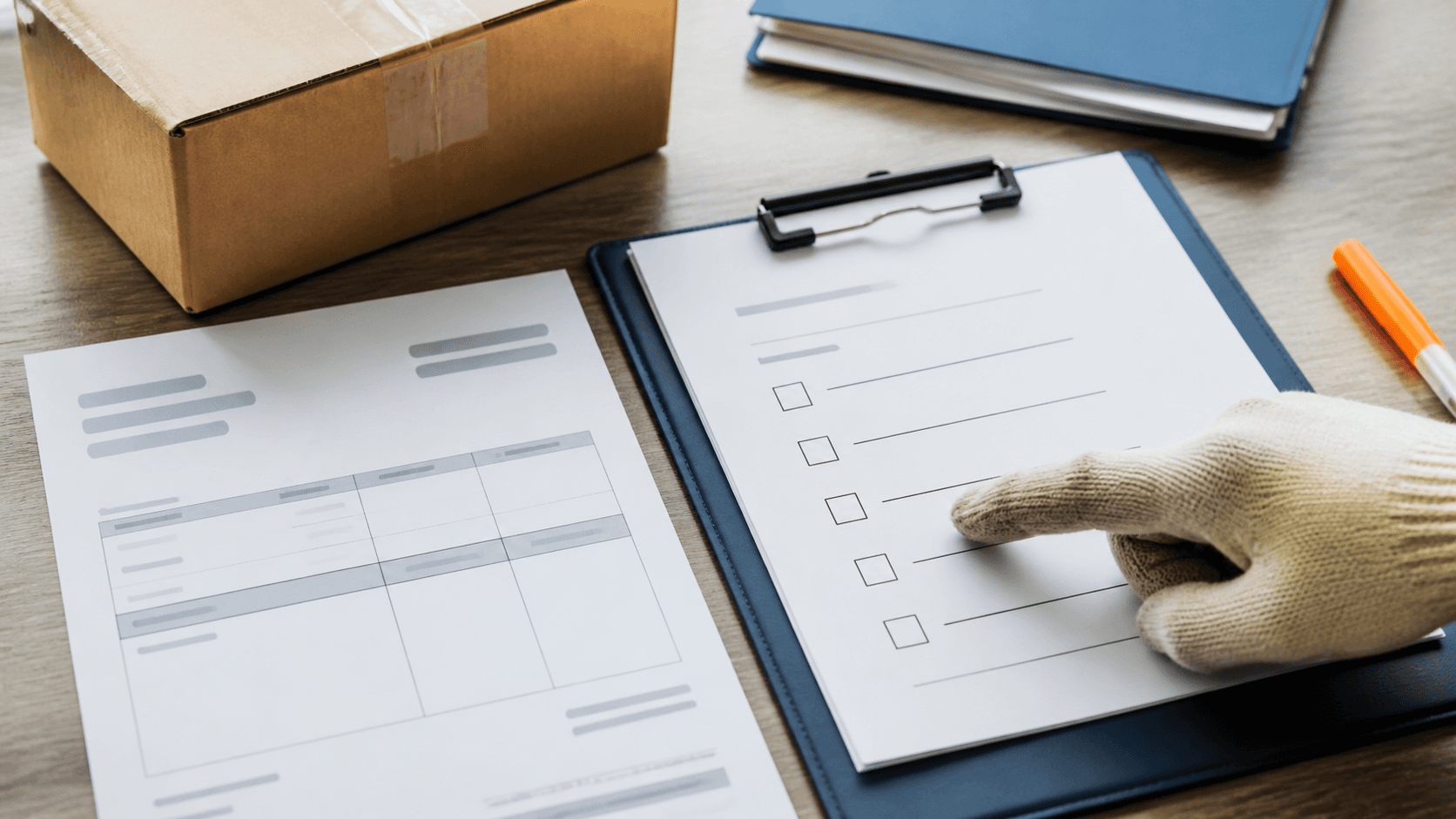 Close view of an unbranded carton, a blank reconciliation checklist and import paperwork on a desk